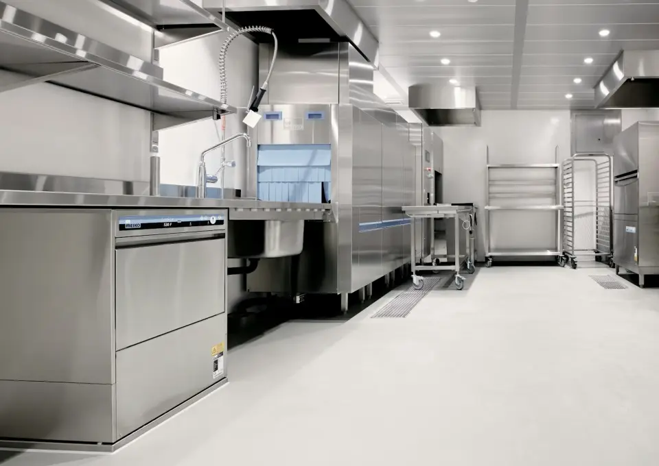 Cocina industrial de acero inoxidable con lavavajillas y estanterías metálicas