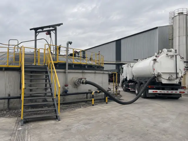 Estanque de riles en una industria con un camión de succión conectado por manguera
